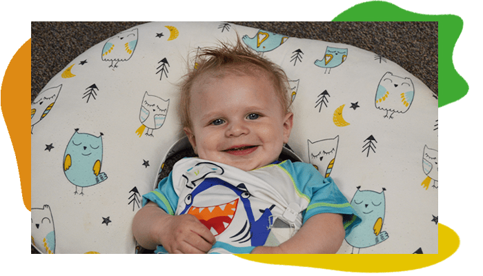 Infant smiling and laying down.